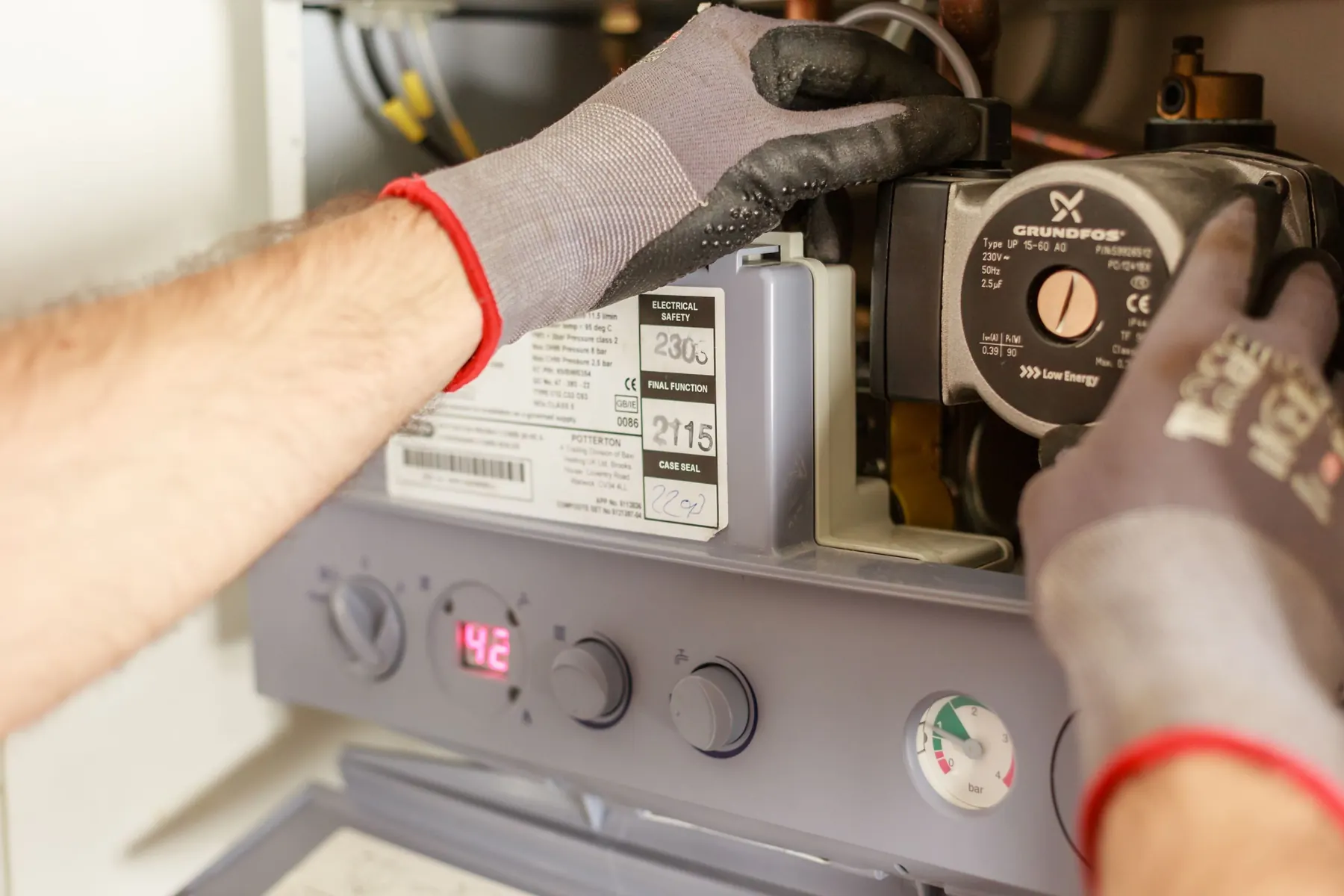 Gloved hands adjusting the controls on a boiler